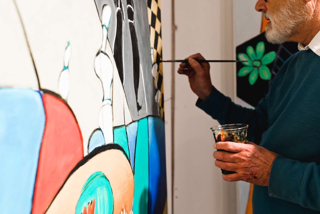 Father Jerome Tupa at work on a large canvas, brush in hand