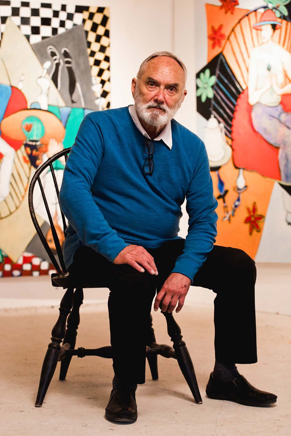 Father Jerome Tupa seated in his studio, surrounded by his bold, colorful canvases