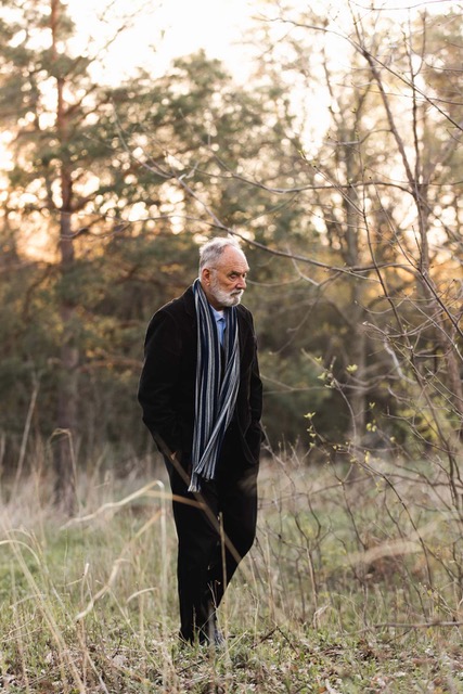 Father Jerome Tupa walking through a wooded landscape at dusk in Collegeville, Minnesota